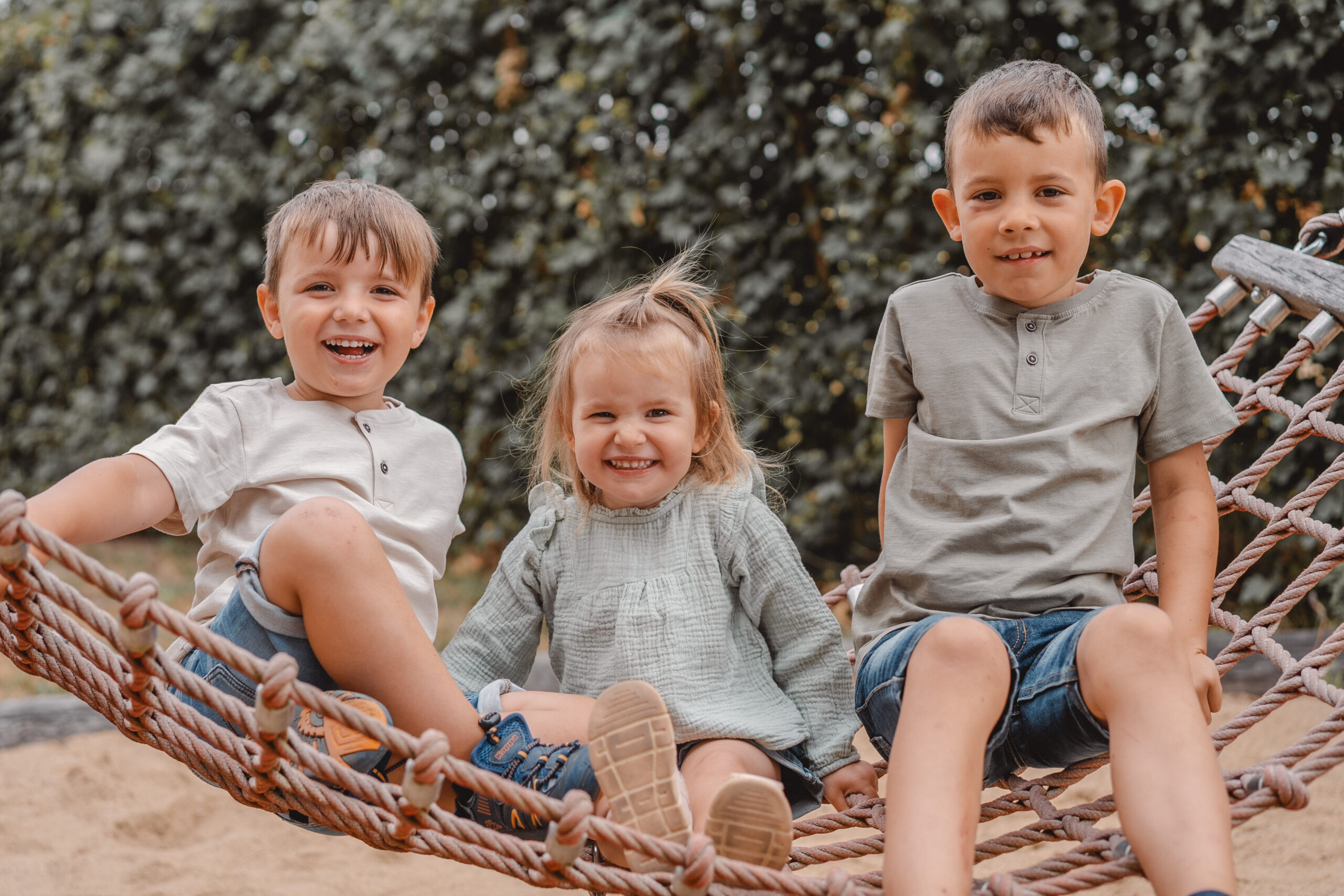 Drei Kinder auf Kletternetz – natürliche Kitafotografie Potsdam